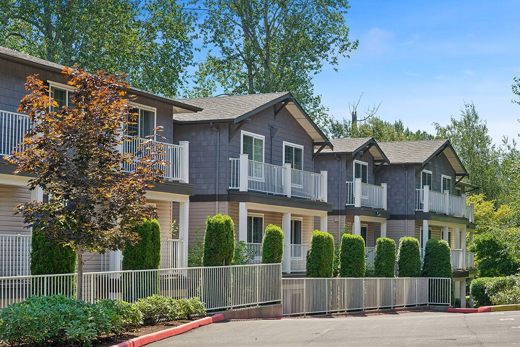 A row of houses with trees in front.